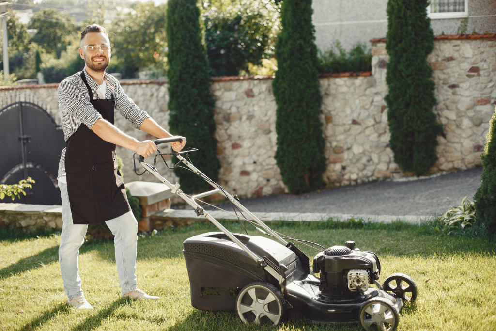 A man using a lawn mower to cut the grass.