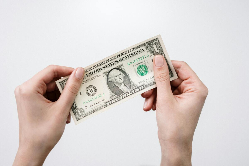Both hands holding a one dollar bill