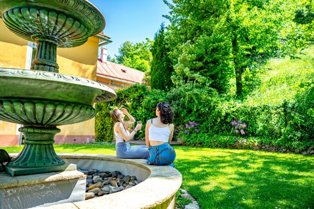 Two people sitting on a fountain in a garden