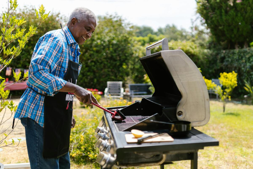 A man grilling barbecue in a landscaped garden