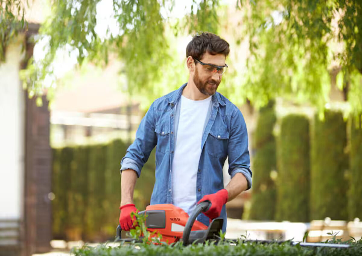 A professional landscaper trimming over grown bush
